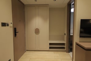 A hotel room with a wardrobe, a television, and a small seating area. - Ananta Elite (Somnath)