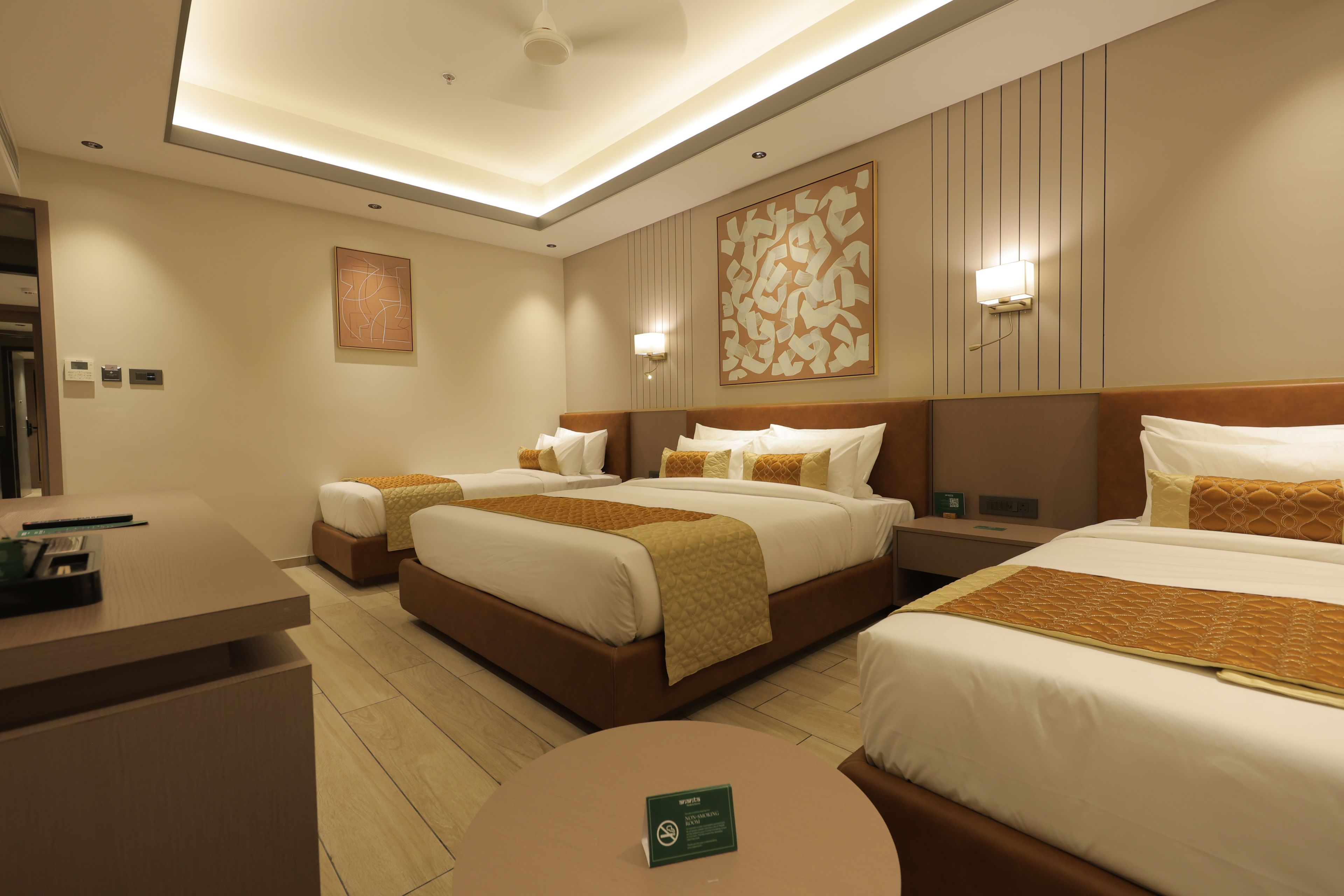 A hotel room with two beds, a desk, and a round table.