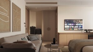A modern hotel room with a sofa, a coffee table, a bed, a TV, and luggage. - Ananta Elite (Somnath)