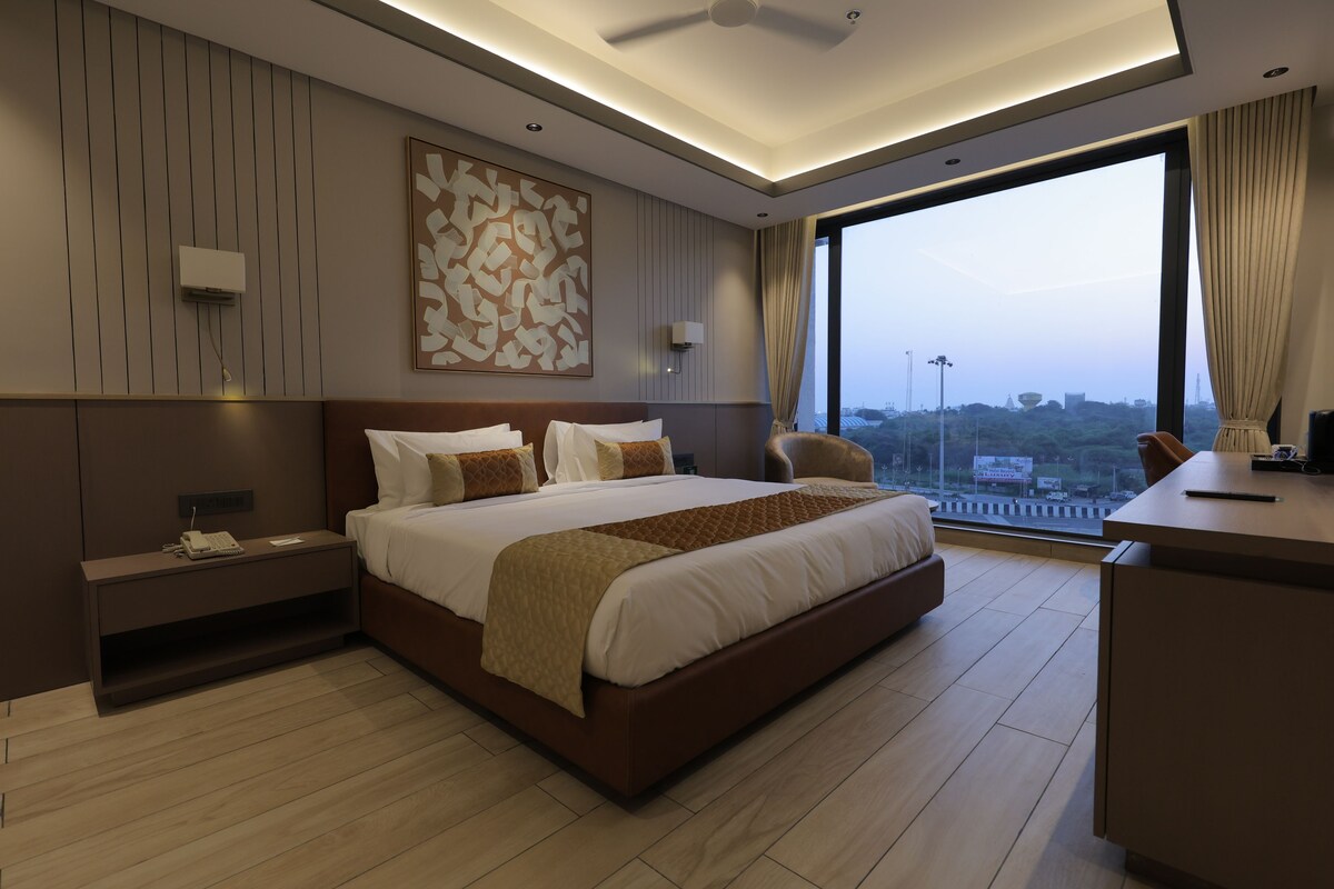 Una habitación de hotel moderna con una cama grande, un escritorio y vistas a la ciudad.