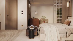 A modern bedroom with a large bed, a seating area with a small table, and a decorative wall panel. - Ananta Elite (Somnath)