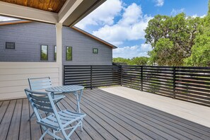 Eine überdachte Terrasse im Freien mit Tisch und Stühlen, einem Holzzaun und einem Gebäude im Hintergrund.