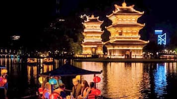 Un pagada tradicional de varios niveles iluminada por la noche, reflejada en aguas tranquilas.