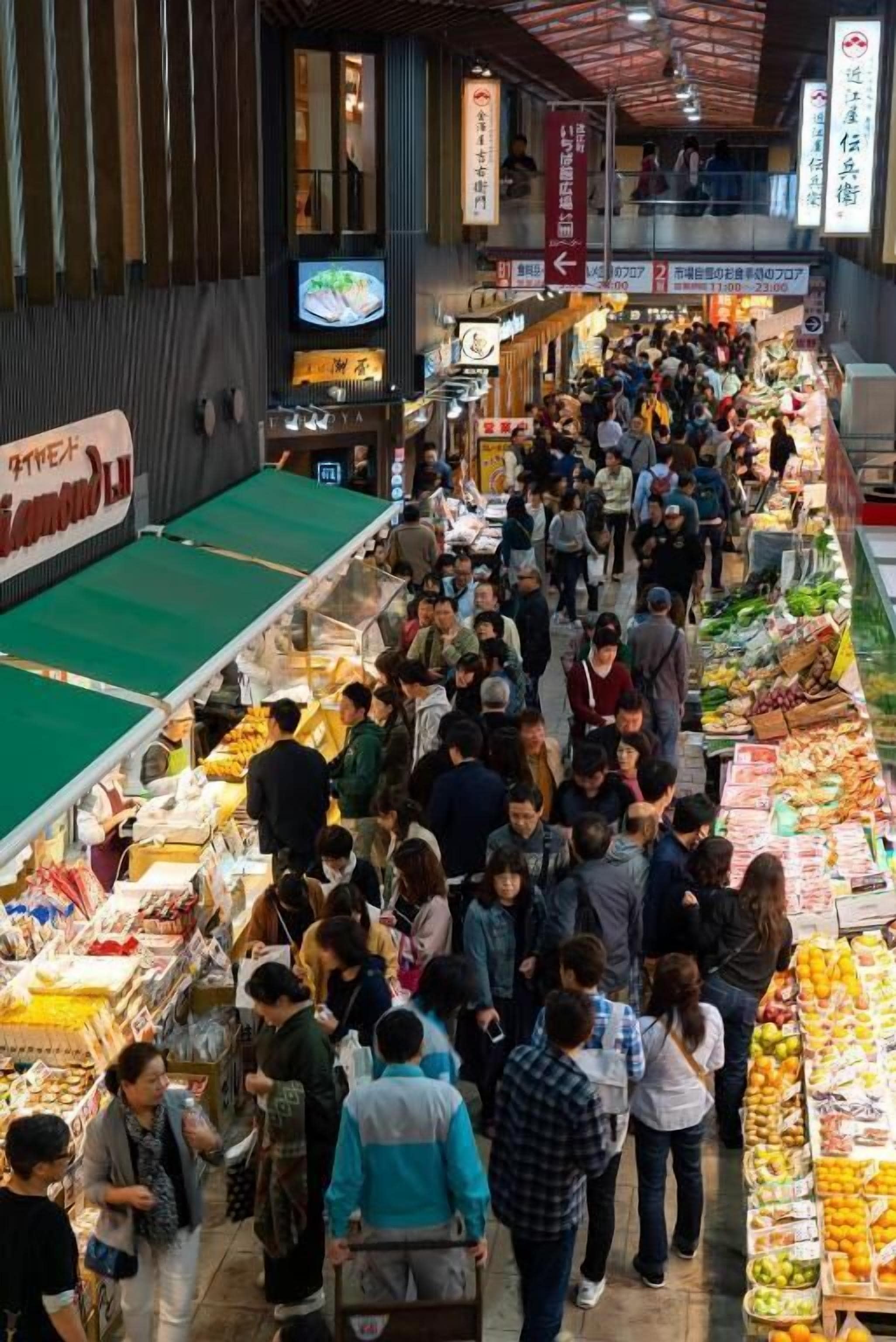 A crowded indoor market with various stalls and people shopping.