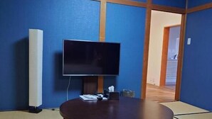 A room with tatami flooring, a round table, and a flat-screen TV. - annex kanazawa (Kanazawa)