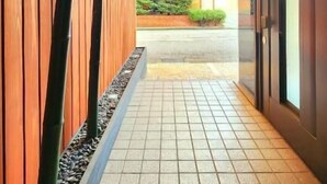 A corridor with wooden paneling, tiled flooring, and a view into a building with a brick exterior. - annex kanazawa (Kanazawa)