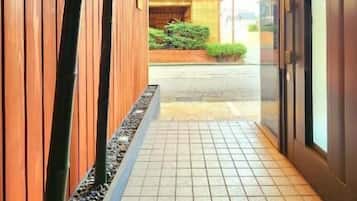 A corridor with wooden paneling, tiled flooring, and a view into a building with a brick exterior.