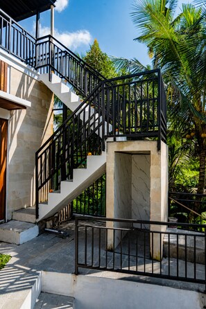 Un escalier avec une rampe en métal noir menant à un palier en pierre.