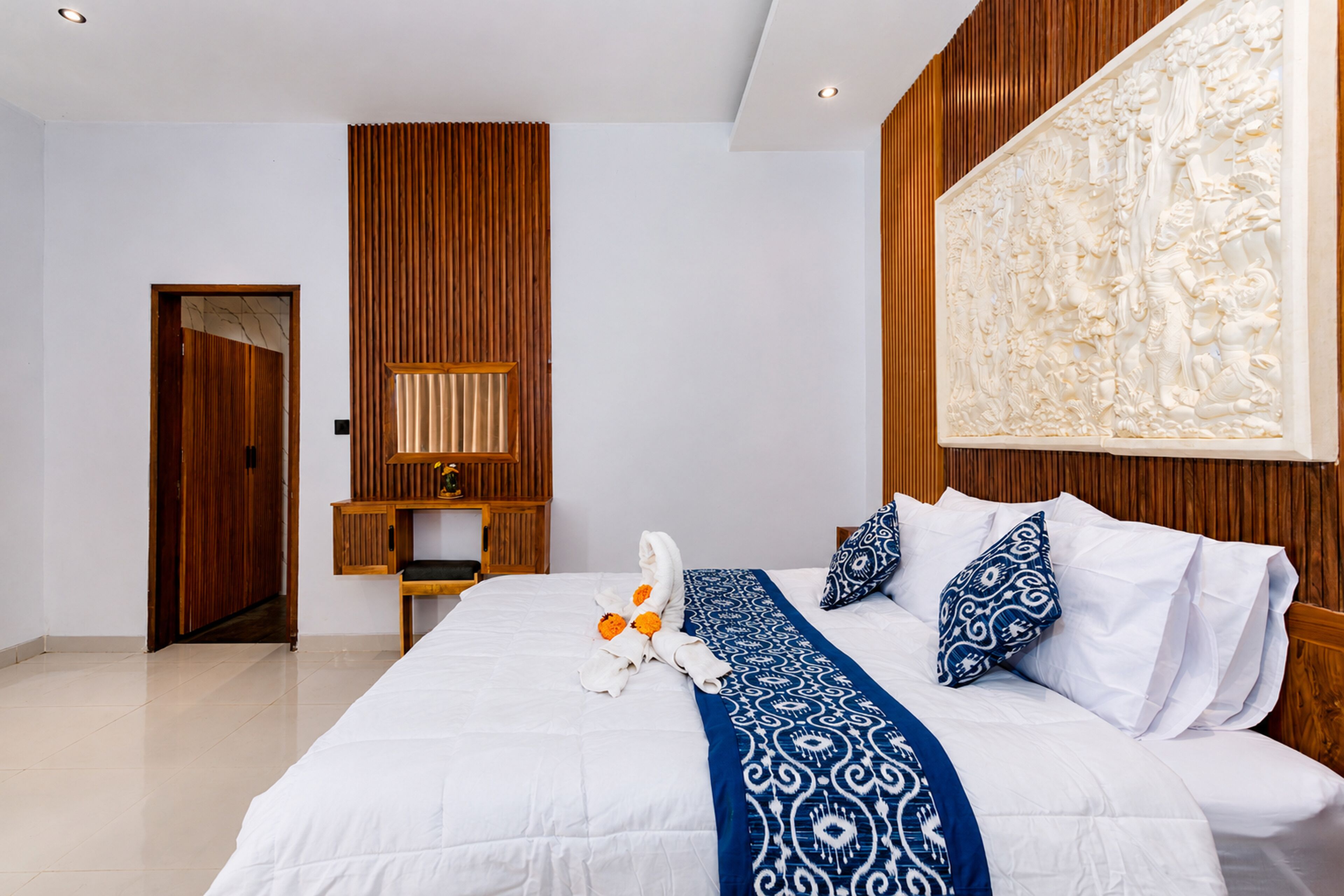 Habitación de hotel con una cama grande, un panel de pared de madera, un escritorio y una obra de arte grande sobre la cama.