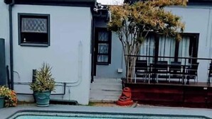 A swimming pool with clear water, surrounded by a house with a tiled roof and a small garden area. - Romantic Retreat Private Room with Shared Pool in Gqeberh (Gqeberha)