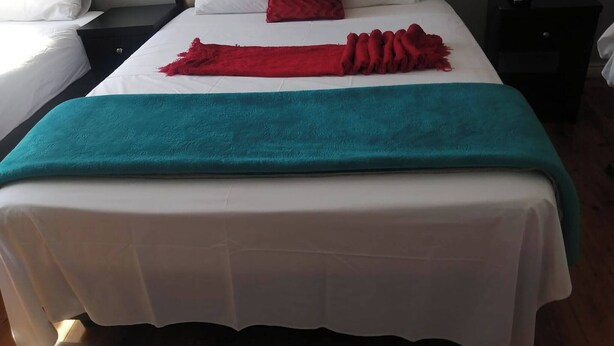A neatly made bed with a white duvet, a teal throw blanket, and a red pillow. - Romantic Retreat Private Room with Shared Pool in Gqeberh (Gqeberha)