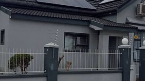 A residential building with a grey facade, a tiled roof, and a gated entrance. - Romantic Retreat Private Room with Shared Pool in Gqeberh (Gqeberha)