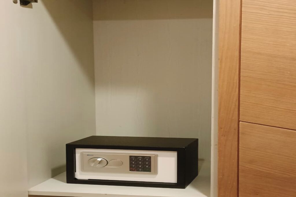 A safe placed on a white surface, likely a shelf or counter, in a room with wooden paneling.