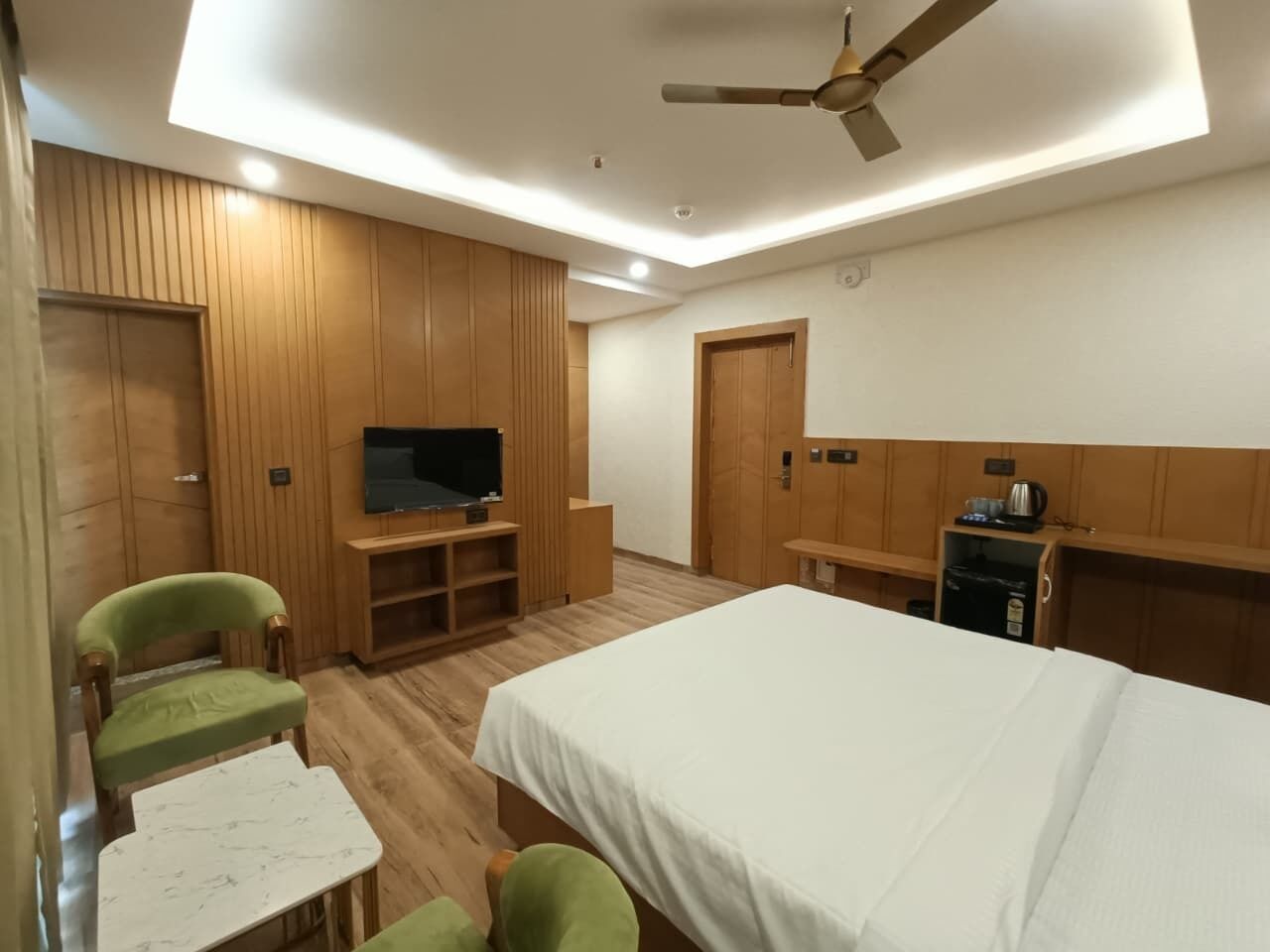 Una habitación con cama, televisor, escritorio y una silla.