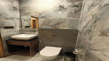 A bathroom with a marble wall, a sink, a toilet, and a mirror.