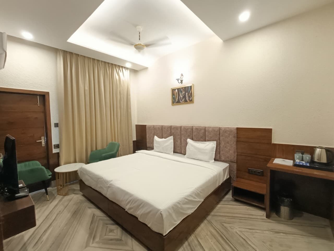 Habitación de hotel con una cama grande, un escritorio, una silla, un televisor y un ventilador de techo.