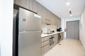 A modern kitchen with stainless steel appliances, wooden cabinets, a built-in oven, and a dishwasher.
