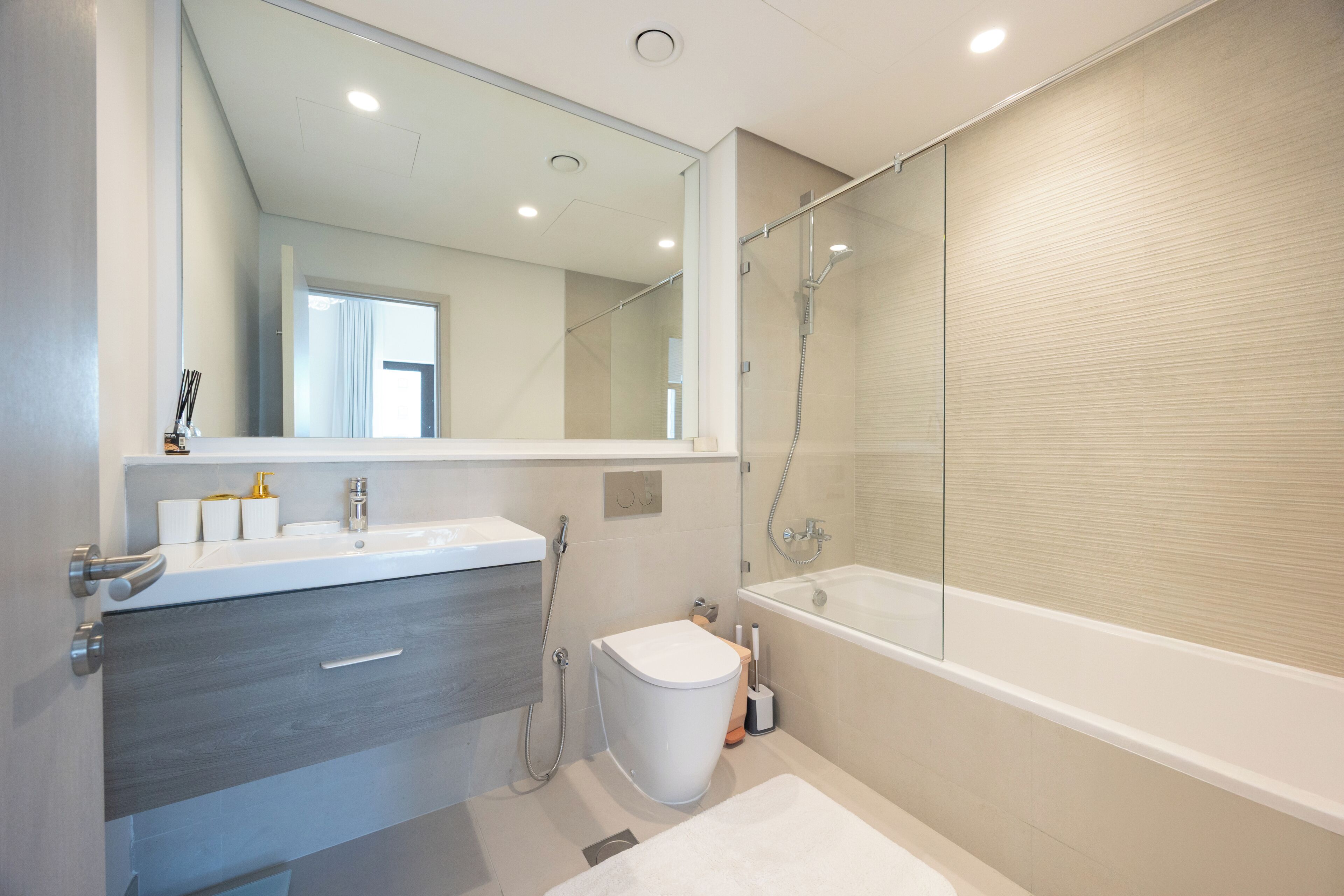 A modern bathroom with a bathtub, a toilet, and a vanity with a mirror.