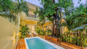 Un jacuzzi rodeado de exuberante vegetación y un edificio con balcones.