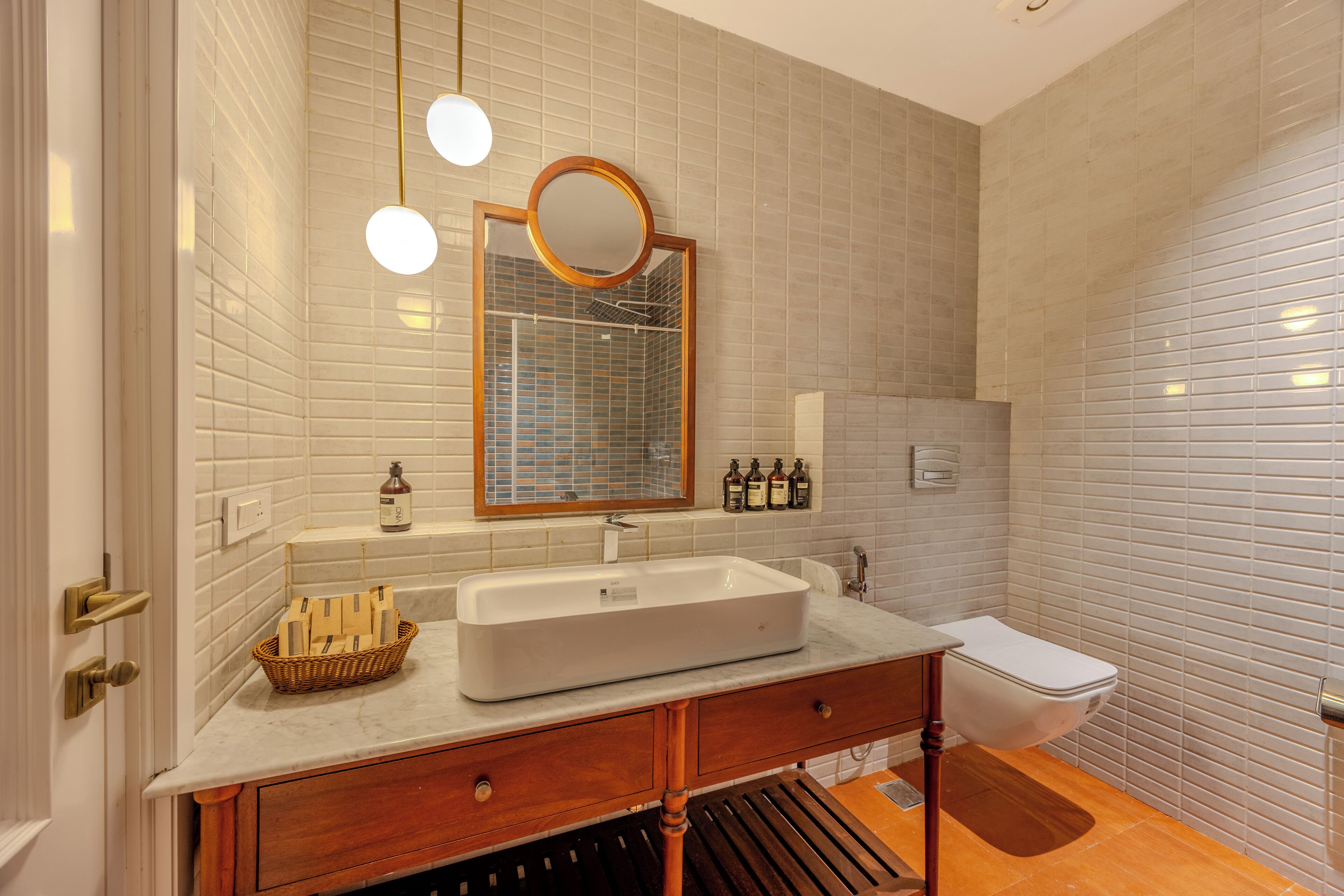Ein Badezimmer mit einem weißen Waschbecken, einem Holz-Waschtisch, einem Spiegel und einer Toilette.