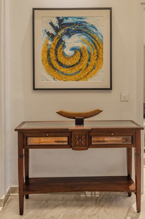 Een houten bureau met lades en een decoratieve schaal erop, in een ruimte met een marmeren vloer.