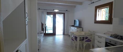 A kitchen with a dining area, a television, and a window.