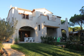 A two-story house with a patio, outdoor seating, and a garden.