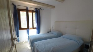 Un dormitorio con dos camas, una ventana con cortinas y piso de baldosas.