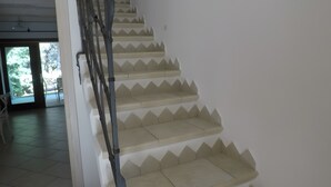 Una escalera con barandilla metálica y escalones color beige que conducen a un piso superior.