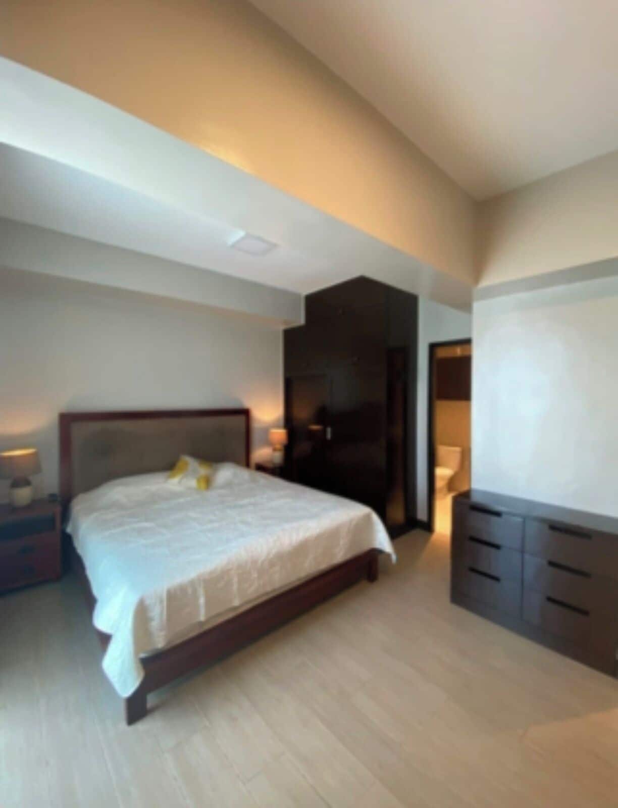Un dormitorio moderno con una cama grande, mesitas de noche, un armario y un televisor.