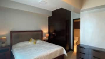 Un dormitorio moderno con una cama grande, mesitas de noche, un armario y un televisor.