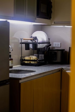A kitchen with a dish rack, a coffee maker, and a microwave.