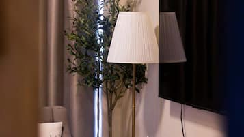 A modern living room with a sofa, a coffee table, a floor lamp, a television, and a large plant.