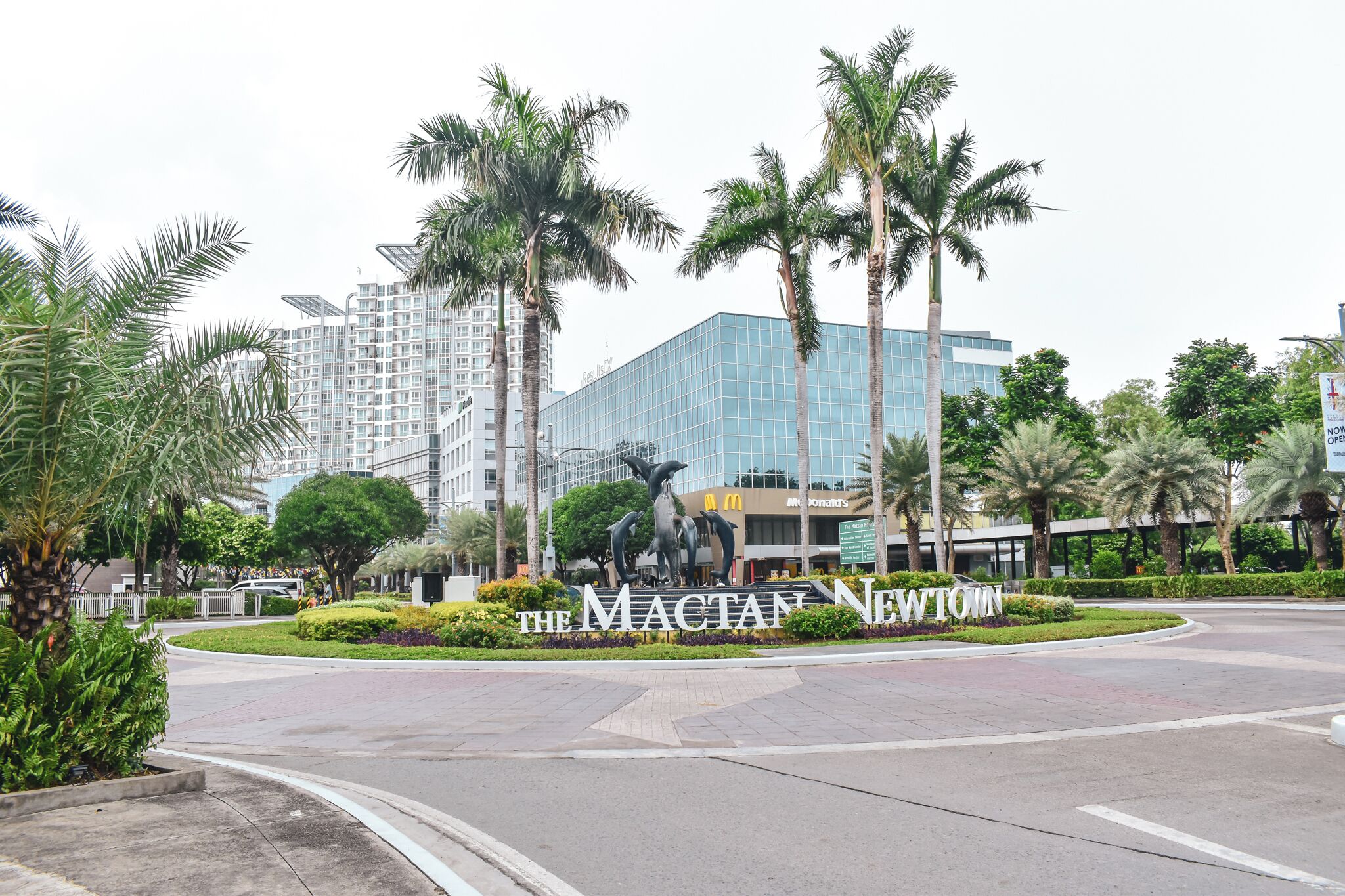 A landscaped area with palm trees, a McDonald's sign, and a building with reflective glass windows.