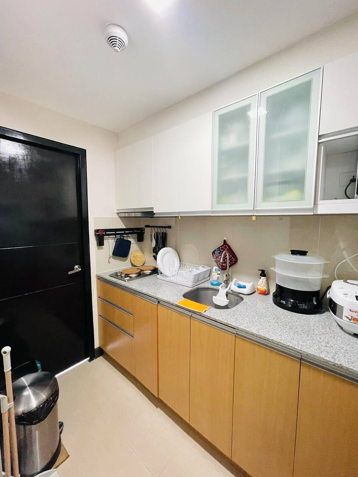 Una cocina con un fregadero, armarios, estufa y un cubo de basura.