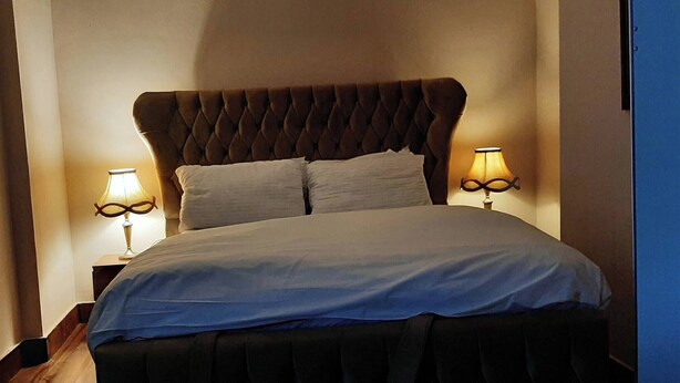 A bed with a tufted headboard, two bedside lamps, and a white bedspread.