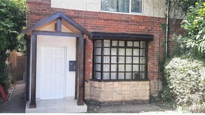 A house with a white door, a small porch, and a window with a grid pattern.