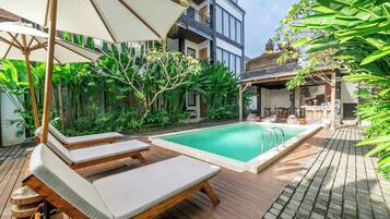 A pool area with lounge chairs and a wooden deck.