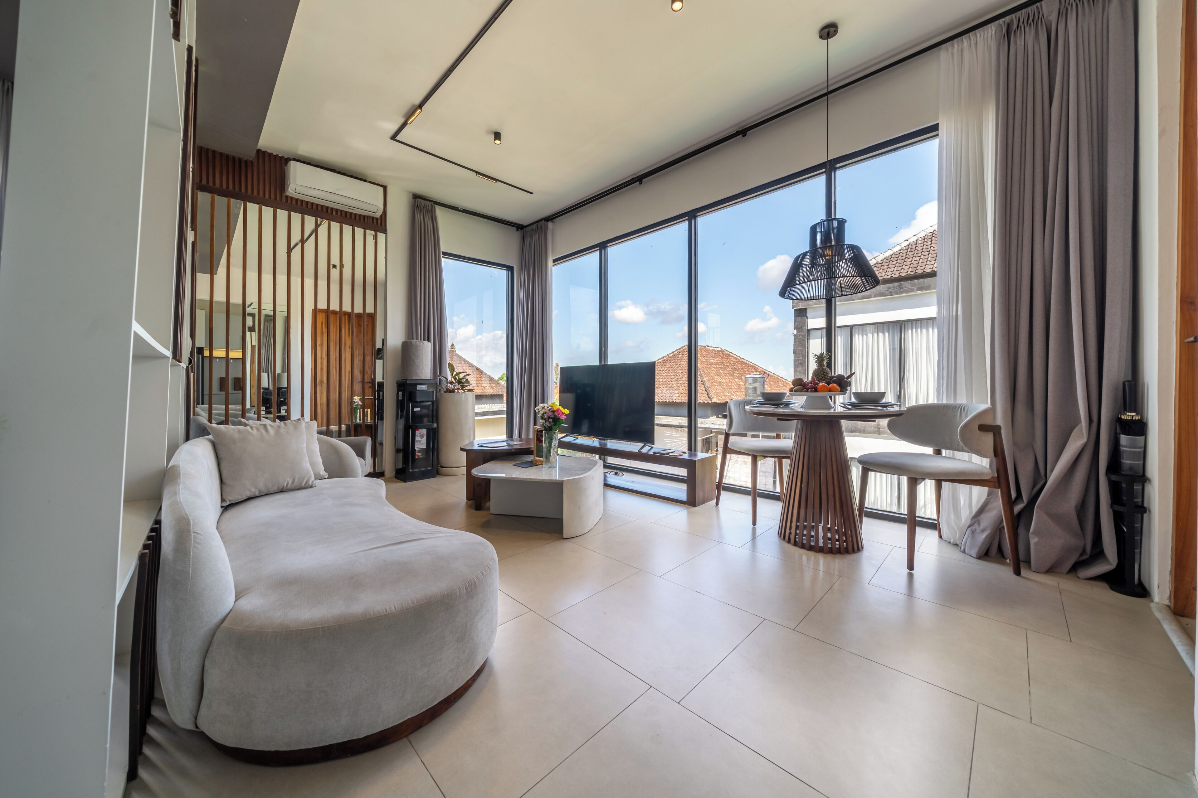 A modern living room with a sofa, a coffee table, and a dining area with chairs and a table.