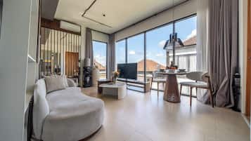 A modern living room with a sofa, a coffee table, and a dining area with chairs and a table.