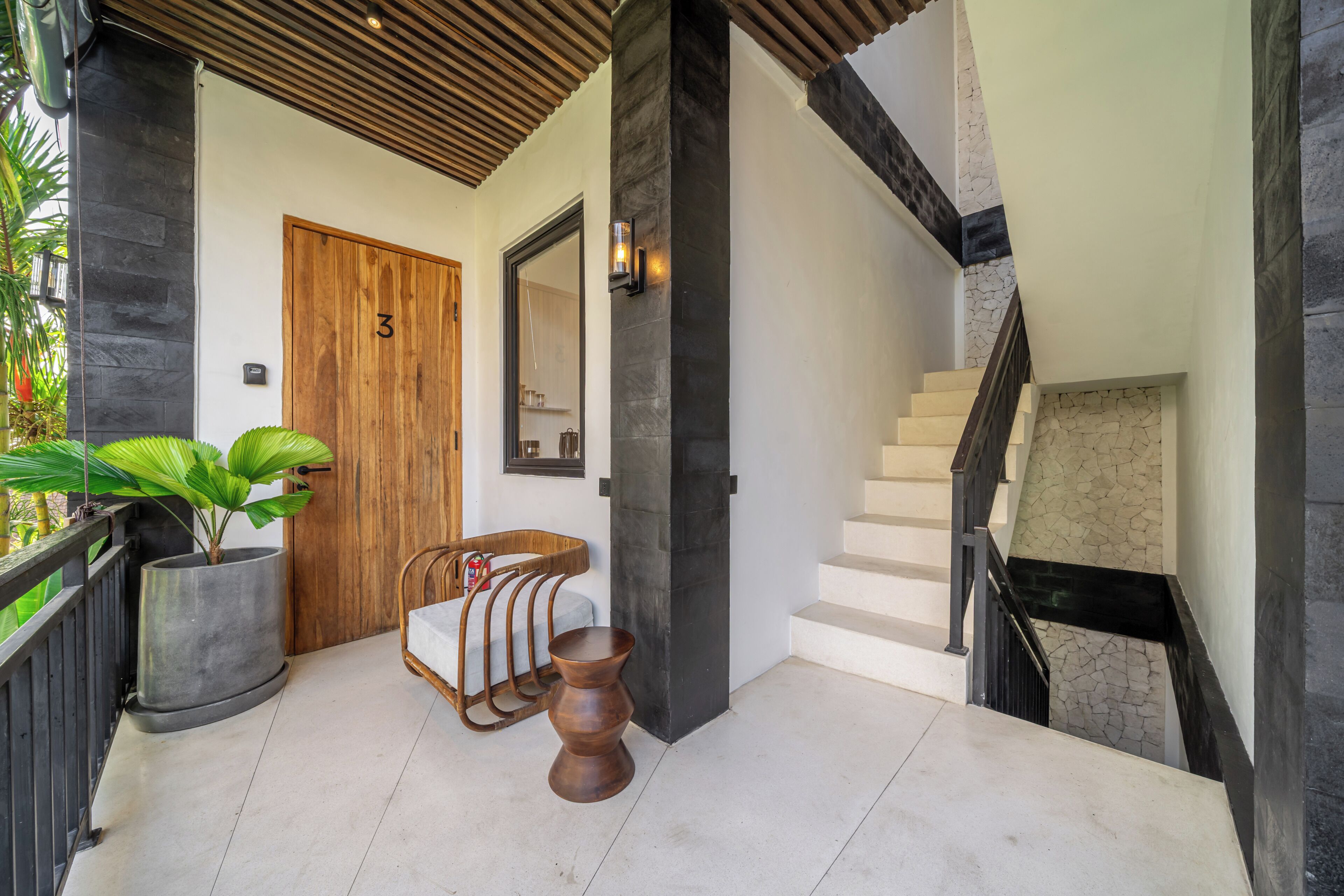 A modern entrance with a wooden door, a staircase, and a seating area with a chair and a table.