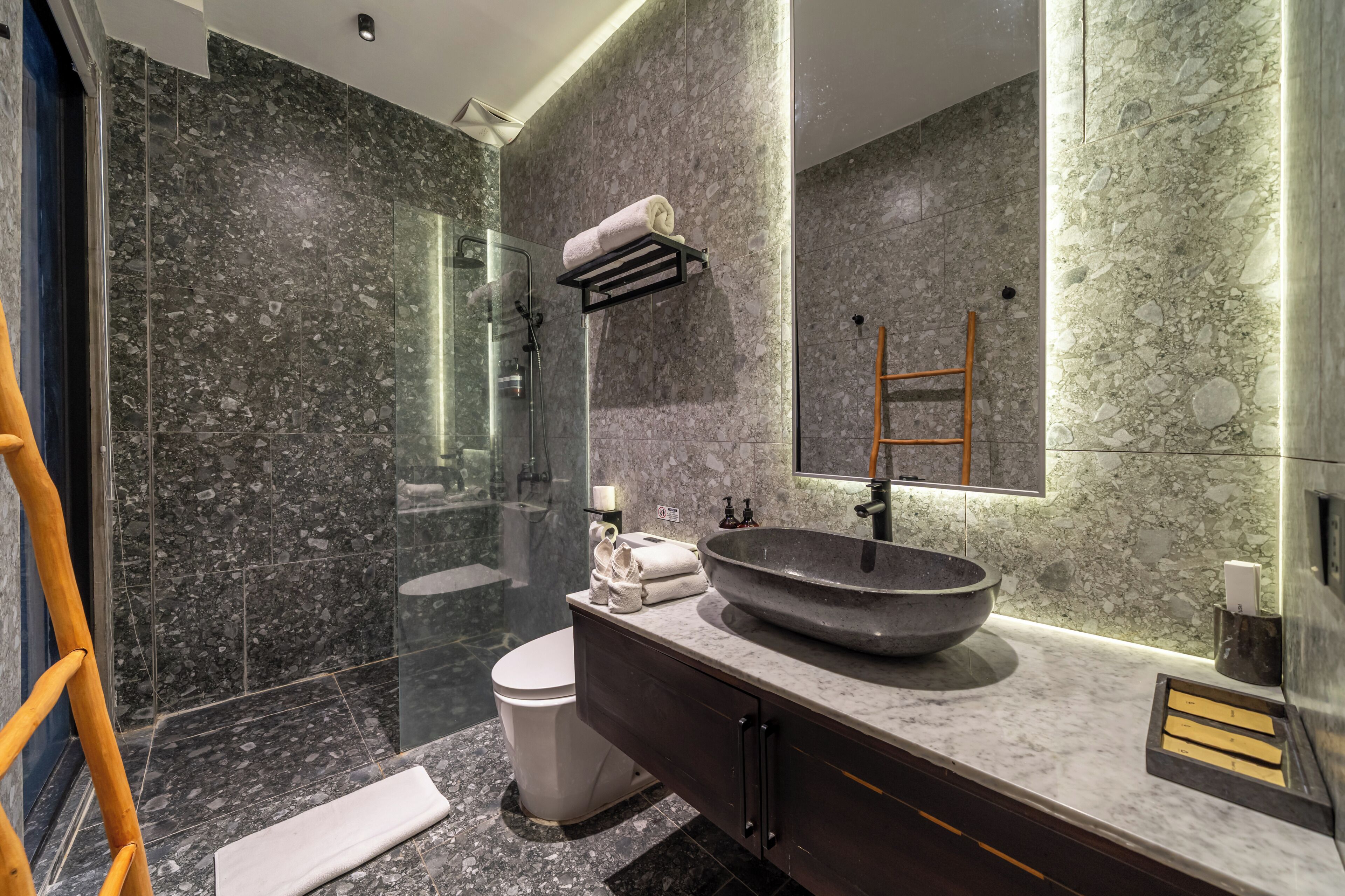 Un baño moderno con un lavamanos grande, cabina de ducha con mampara de vidrio y pared con azulejos de m ármol.