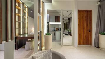 A modern living room with a sofa, a dining area with a table, and a kitchen with a refrigerator.