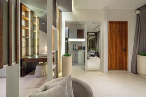 A modern living room with a sofa, a dining area with a table, and a kitchen with a refrigerator. - Sebelas Apartments Ubud (Gianyar)