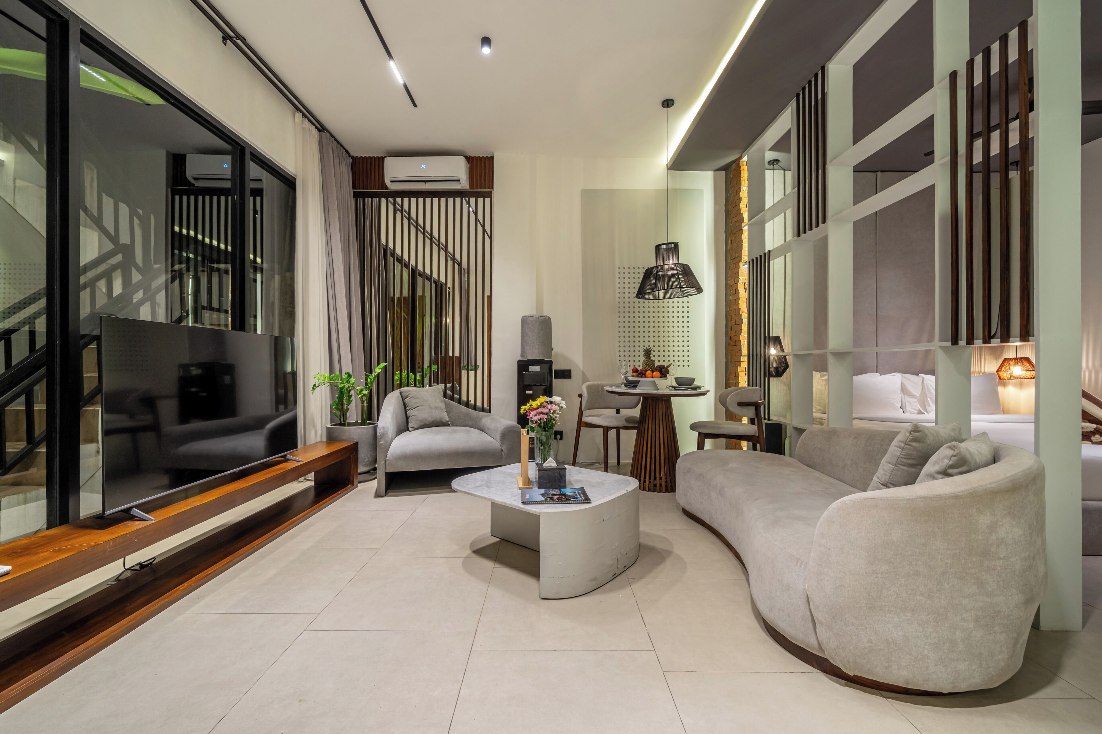 Una sala de estar moderna con un televisor de pantalla plana, un sofá, una mesa de centro y una zona de comedor con una mesa y sillas.