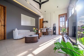 A modern living room with a sofa, coffee table, and a dining area with chairs and a table. - Sebelas Apartments Ubud (Gianyar)