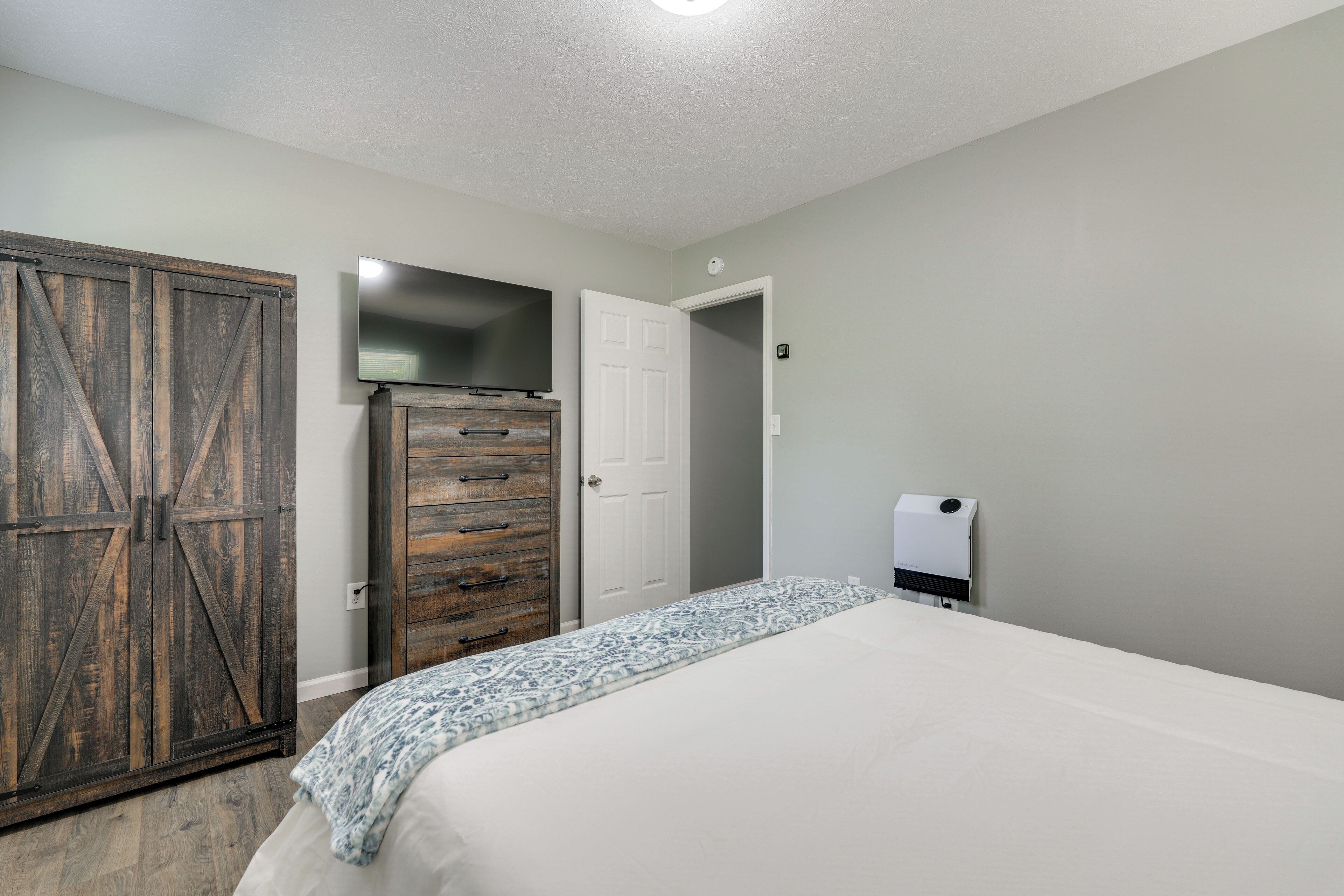A bedroom with a bed, a wardrobe, a television, and a heater.