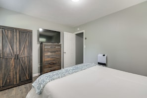 Une chambre à coucher comprenant un lit, une armoire, un téléviseur et un radiateur.