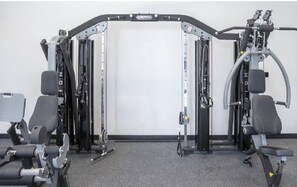 A gym with weightlifting equipment, benches, and a mirrored wall.