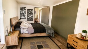 Un dormitorio moderno con cama, mesita de noche y espejo.